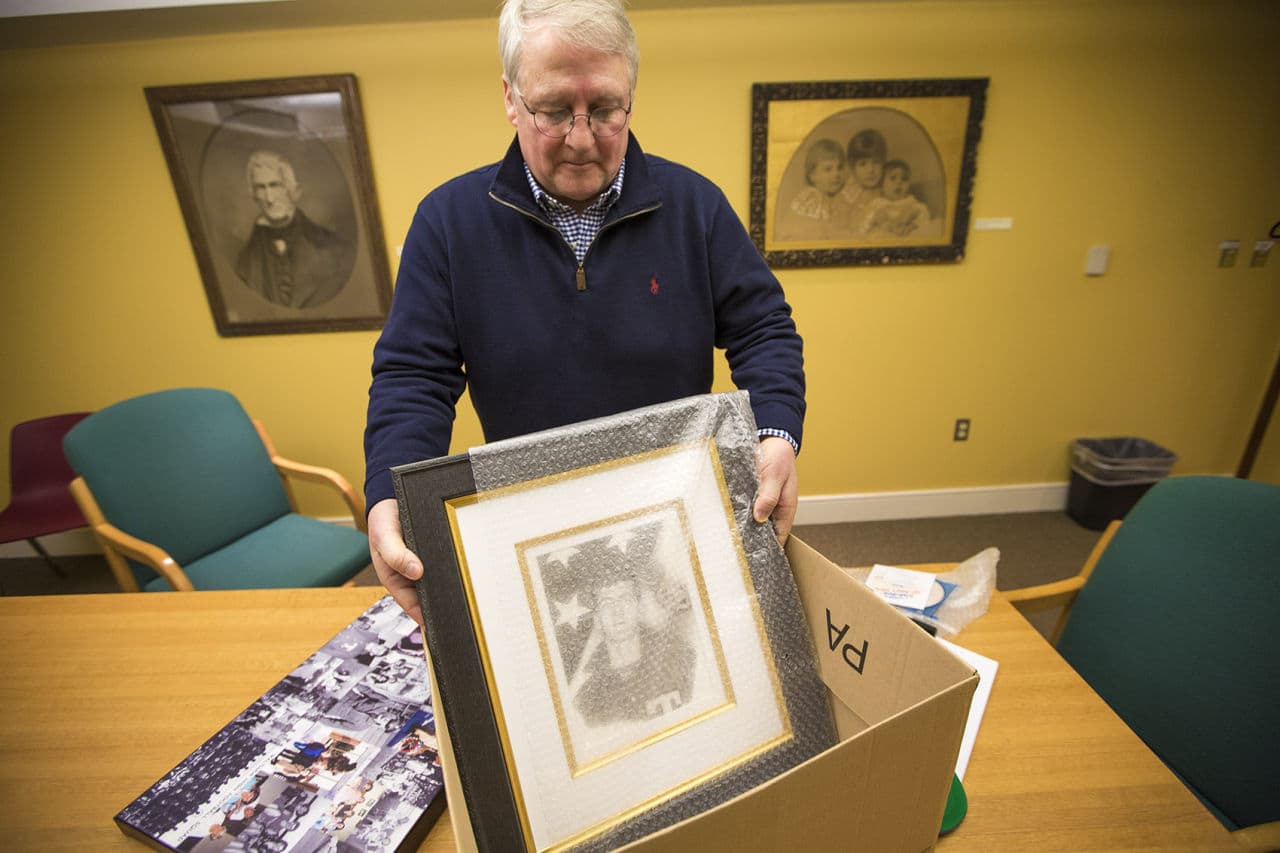 David Cline places a portrait of his uncle, Sgt. Robert Dakin, into a box along with other memorabilia. (Jesse Costa/WBUR)