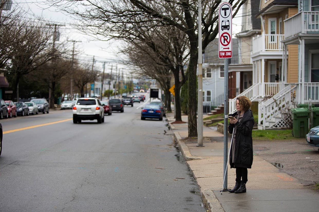 Joann Becker stands at a Watertown bus stop, which she hopes will be easier for visually impaired people to locate with a new mobile app she's working on at the Perkins School for the Blind. (Jesse Costa/WBUR)