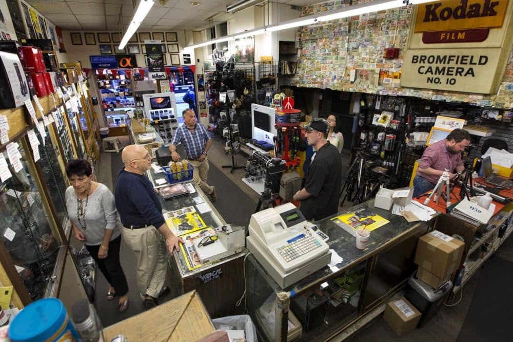 Bromfield Camera is a mainstay of Bromfield Street. Steve Centamore (left, in blue behind counter) advises a customer about selling some camera equipment. (Jesse Costa/WBUR)