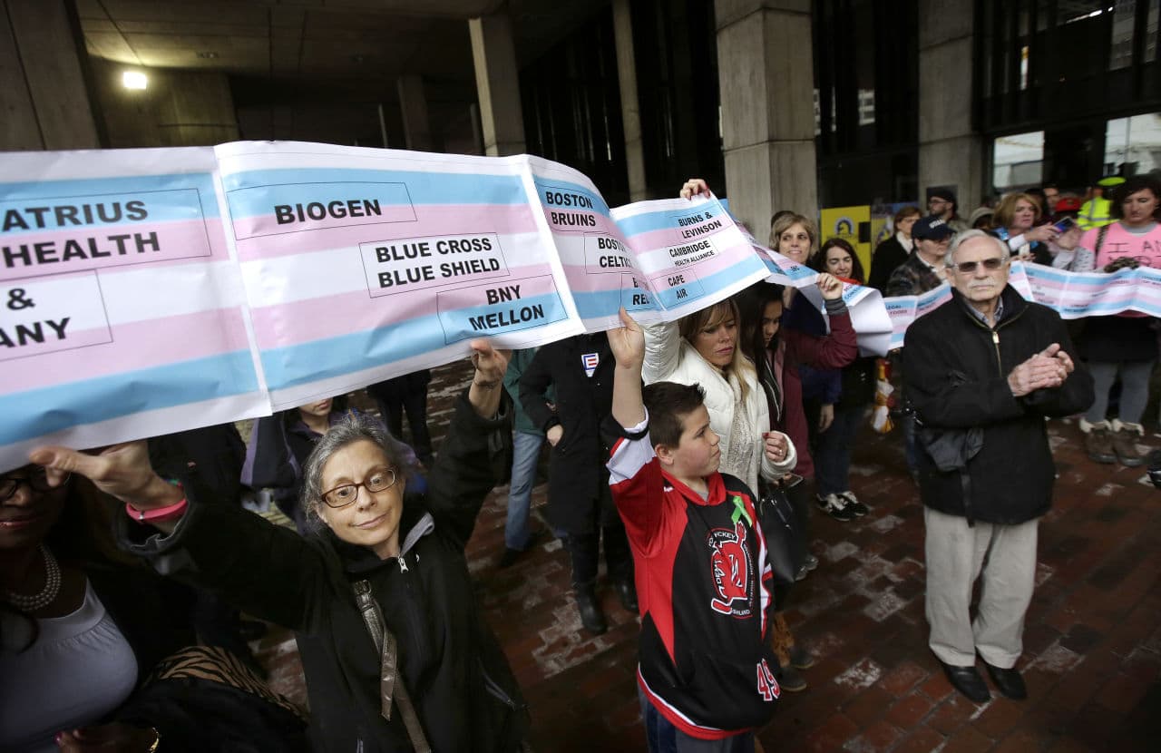 Lori Gillen displays a banner with the names of businesses that she said support the transgender community during a ceremony commemorating the raising of a flag representing the transgender community at Boston City Hall. (Steven Senne/AP)