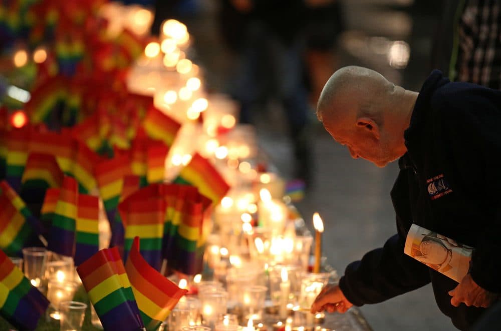 A man places a candle at an impromptu memorial set up in Sydney on Monday following the Orlando attack. Australian Prime Minister Malcolm Turnbull said that the Orlando mass shooting was "an attack on all of us, on all our freedoms, the freedom to gather together, to celebrate, to share time with friends." (Rick Rycroft/AP)