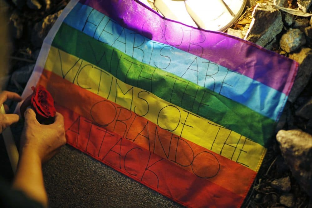 A person places a rose by a flag during a vigil at The Center, a community center for the LGBT community, on Sunday in Las Vegas. (John Locher/AP)