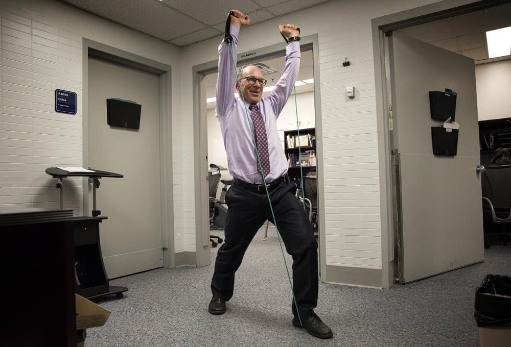 Dr. Eddie Phillips uses resistance tubing to work his arms at his office. (Robin Lubbock/WBUR)