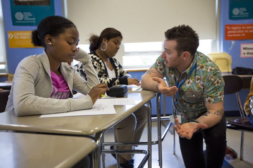 Teacher Tommy Simmons helps a student with one of the Supreme Court cases they're given to review. He says he wanted his students to get an in-depth perspective of the law by interacting with practicing attorneys. (Jesse Costa/WBUR)