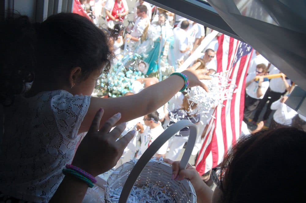 6-year-old Camila Echevarria tosses confetti down from the window of Gloucester’s Mother of Grace Club onto the statue of St. Peter during the Fiesta’s Sunday Procession, June 26, 2016. (Greg Cook)