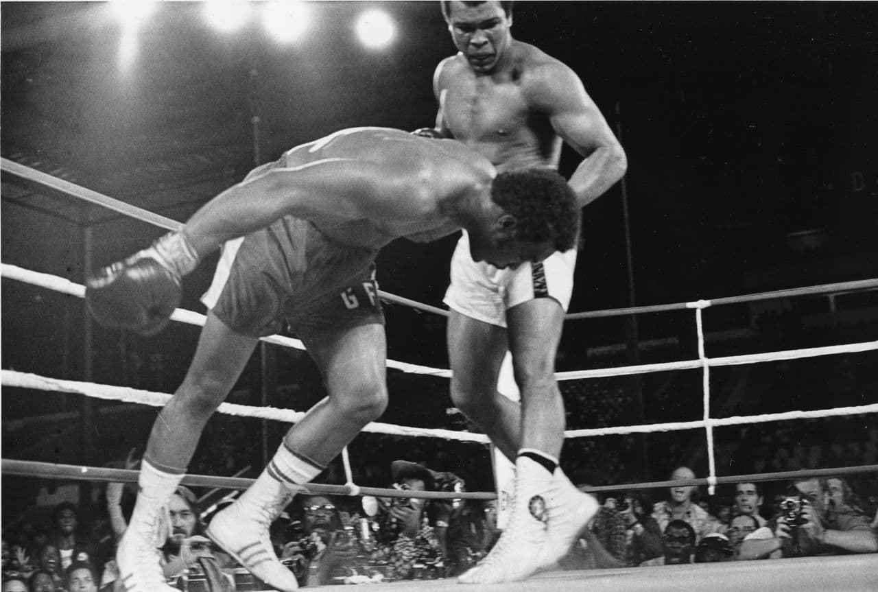 In this Oct. 30, 1974 photo, Muhammad Ali watches as defending world champion George Foreman goes down to the canvas in the eighth round of their WBA/WBC championship match in Kinshasa, Zaire. (AP)
