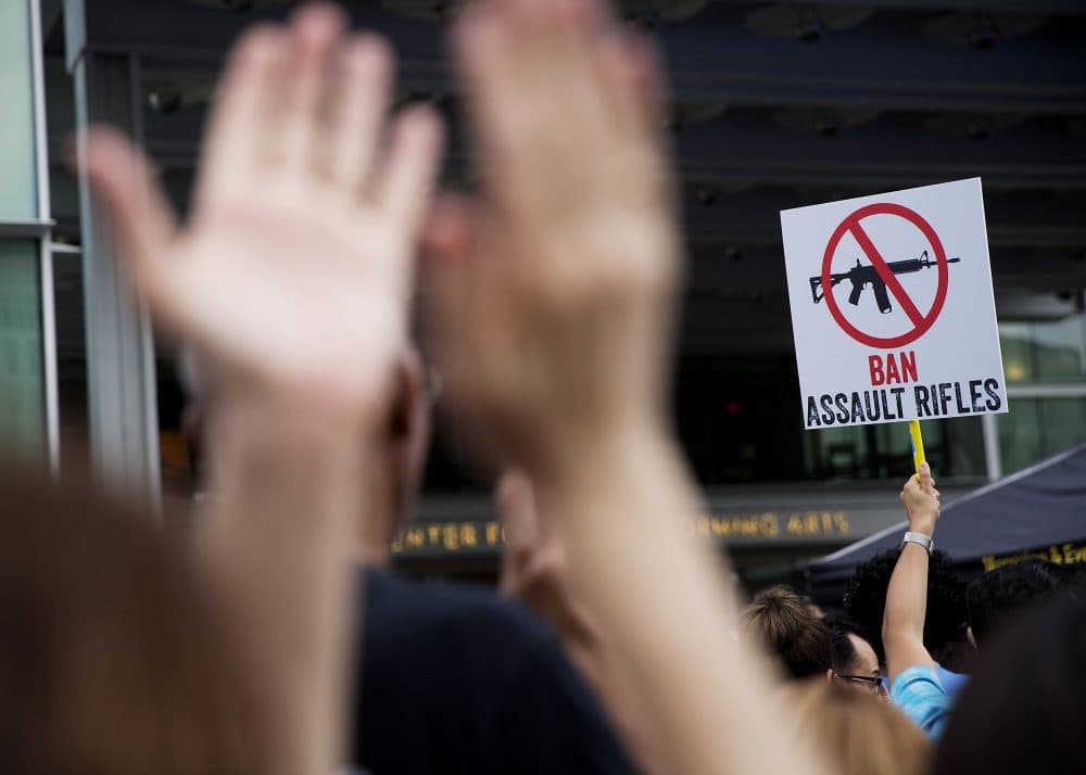A crowd member holds up a sign as audience members applaud during a speech at a vigil downtown for those killed in a mass shooting at the Pulse nightclub Monday, June 13, 2016, in Orlando, Fla. It was the deadliest mass shooting in modern U.S. history. (David Goldman/AP)