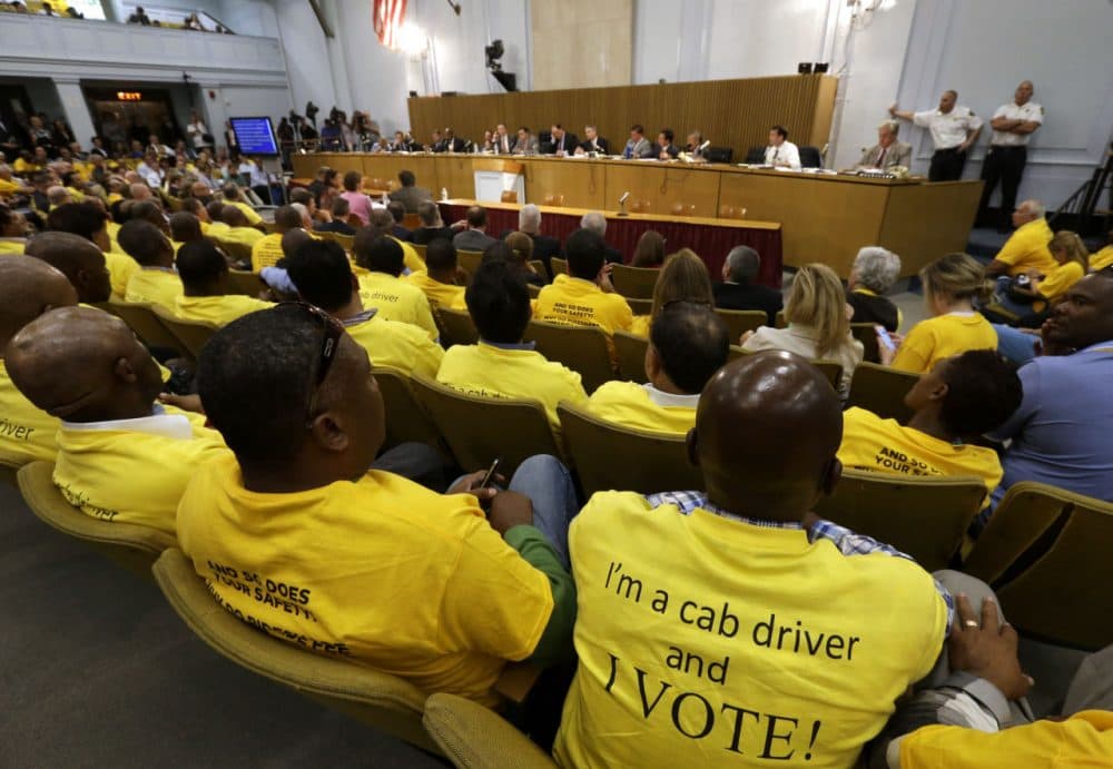 Taxi drivers wearing yellow T-shirts sit together during a hearing on the regulation of ride-hailing companies such as Uber and Lyft, at the State House in Boston last year. (Steven Senne/AP)