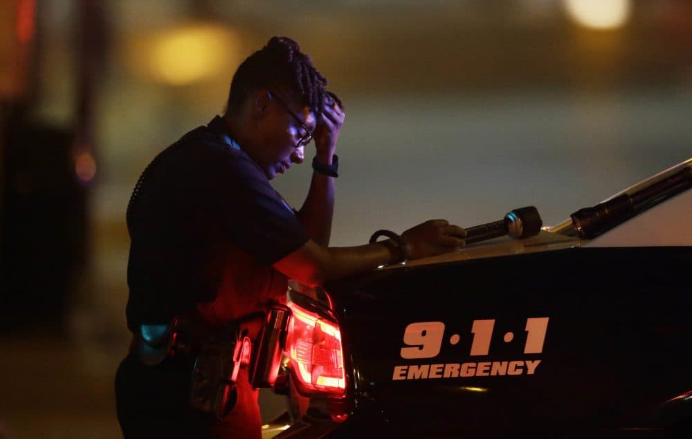 A Dallas police officer, who did not want to be identified, takes a moment as she guards an intersection in the early morning after a shooting in downtown Dallas on Friday. (LM Otero/AP)