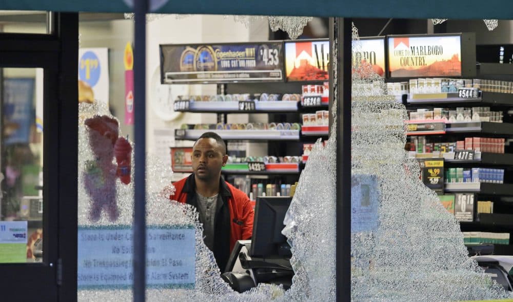 A clerk looks at broke windows shot out at a store in downtown Dallas on Friday. (LM Otero/AP)
