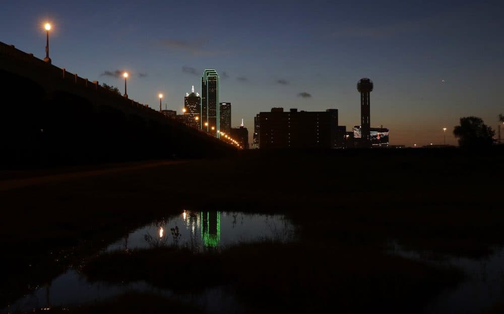 Reunion tower, right, stands with the lights out as the sun rises over downtown Dallas early Friday. Many Dallas businesses turned out their lights to honor the police killed and wounded in an attack Thursday evening. (Eric Gay/AP)