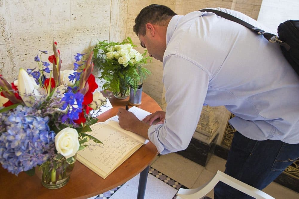 A man signs the condolence book in the lobby of the French Consulate in Boston. (Jesse Costa/WBUR)