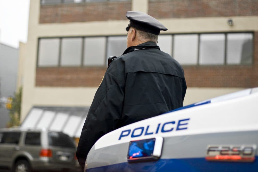 A Boston police officer waits outside his car in the Fenway area. (zaigee/Flickr)