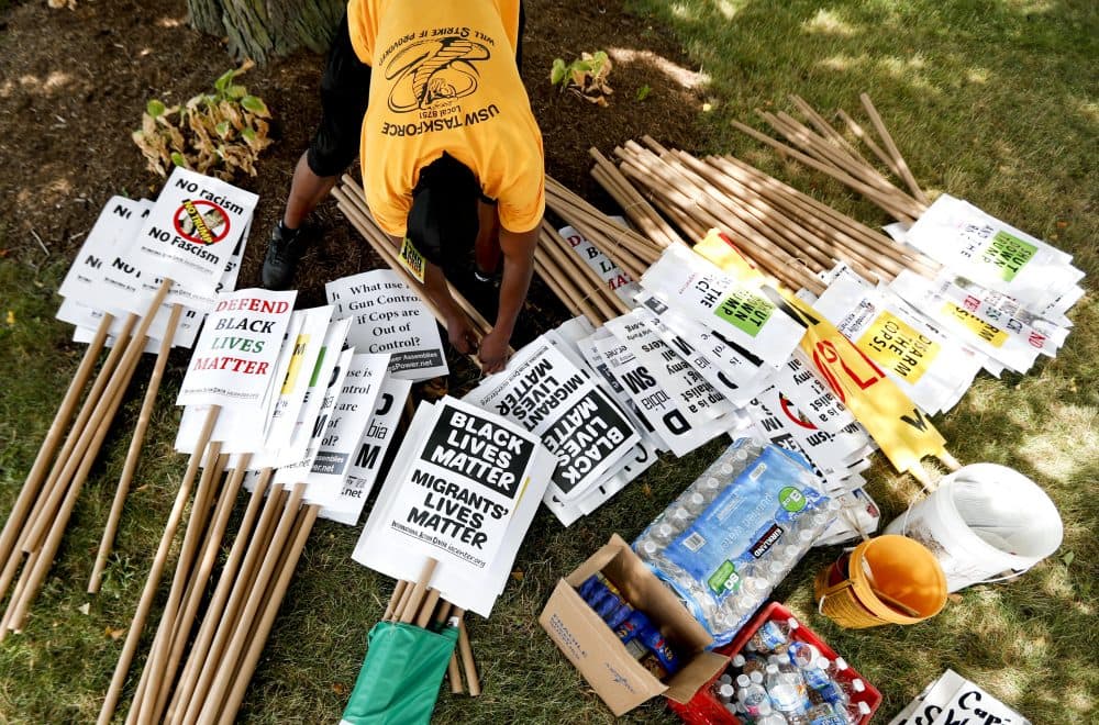 A demonstrator organizes protest signs on Sunday in preparation for the RNC to start on Monday. (John Minchillo/AP)