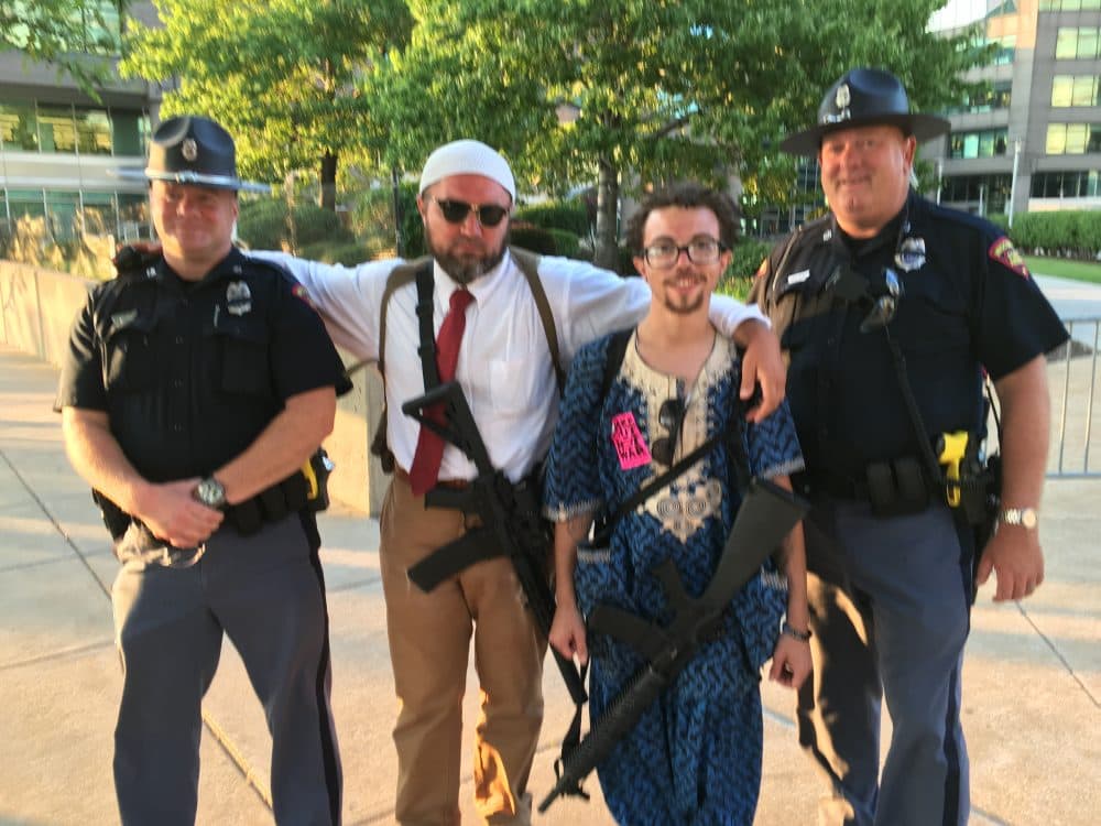 Ohioans Micah Naziri (middle left) and James Campbell (middle right) stand with officers from the Wisconsin State Patrol. Naziri and Campbell are carrying AR-15s. (Alex Ashlock/Here &amp; Now)