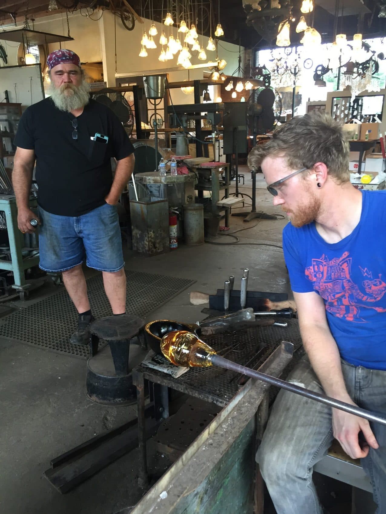 Bart Hanick (left), manager of Cleveland Art, looks on while glassblower Chris Adamick works on a new piece. (Robin Young/Here &amp; Now)