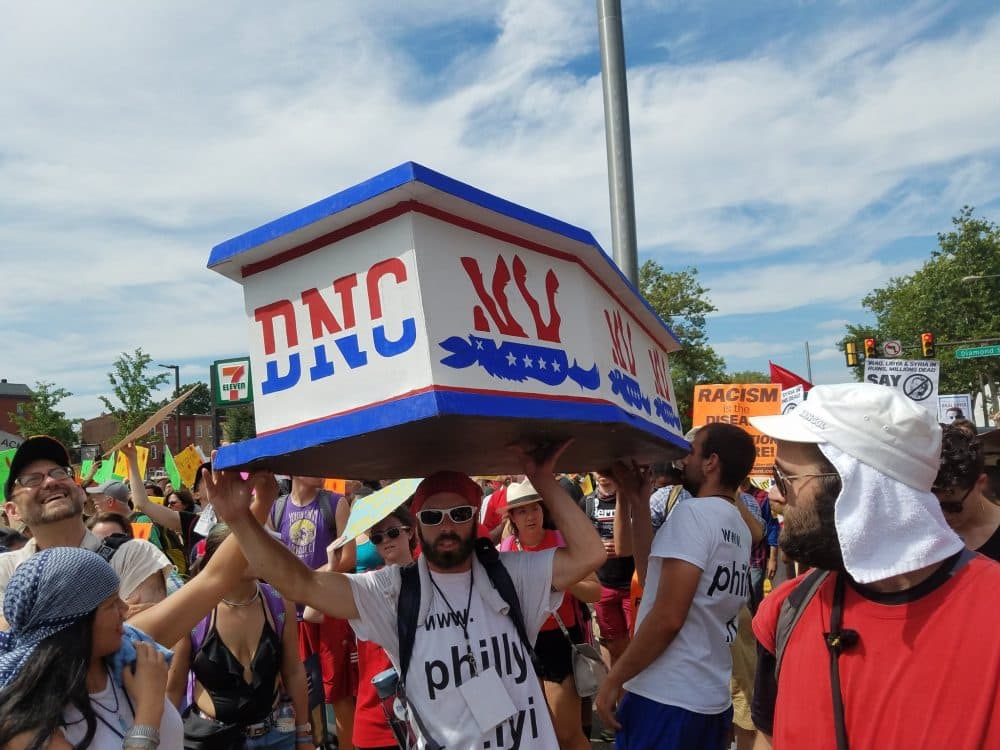 Protesters in Philadelphia carry a red, white and blue casket labeled &quot;DNC&quot; through the streets. (Zeninjor Enwemeka/WBUR)