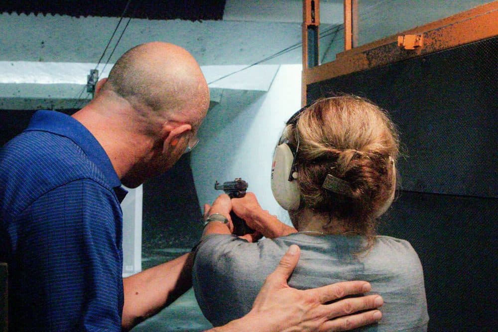 Yuri Zalzman, owner of The Gun Range, gives Here & Now's Robin Young a lesson with a Ruger Mark III. (Dean Russell/Here & Now)
