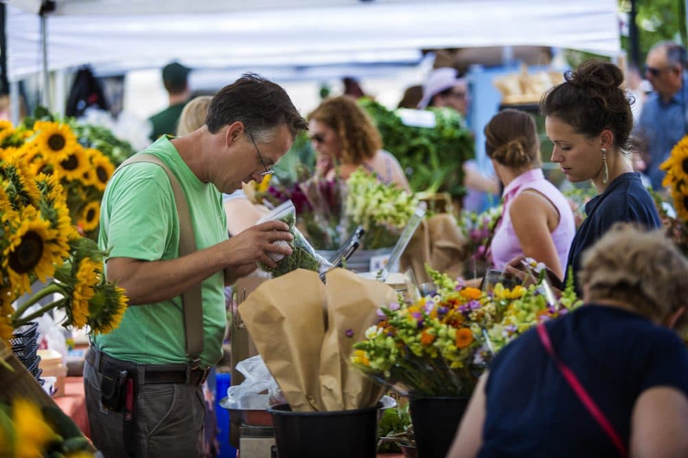 Siena Farms owner Chris Kurth bags up some greens for a patron at the Verrill Farms/Siena Farms stand at the Copley Square Farmers Market. (Jesse Costa/WBUR)