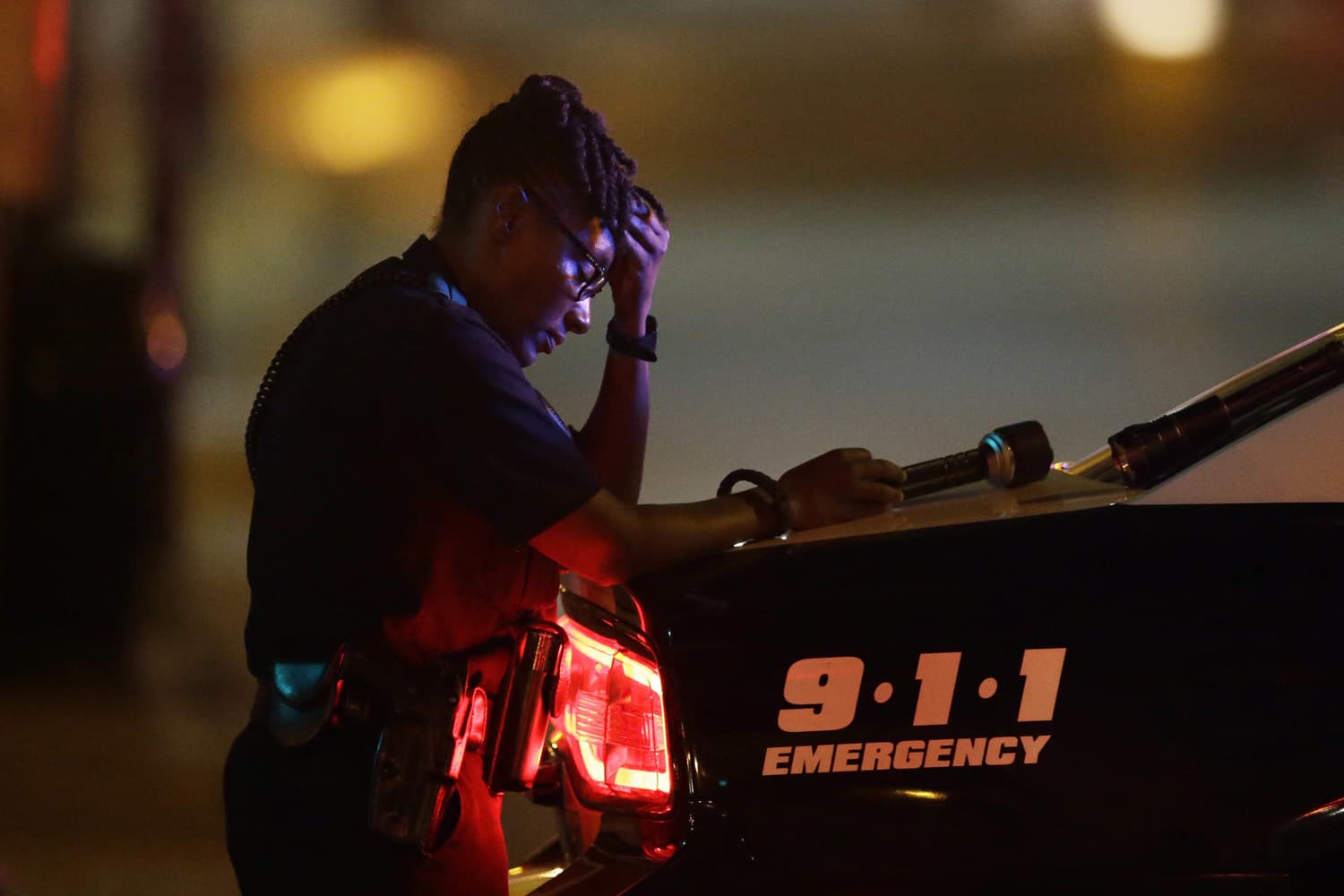A Dallas police officer, who did not want to be identified, takes a moment as she guards an intersection in the early morning after a shooting in downtown Dallas, (LM Otero/AP)