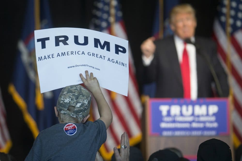 A young attendee holds a sign supporting Republican presidential candidate Donald Trump, right, as he speaks during a campaign event at Watertown International Airport, Saturday, April 16, 2016, in Watertown, N.Y. (John Minchillo/AP)