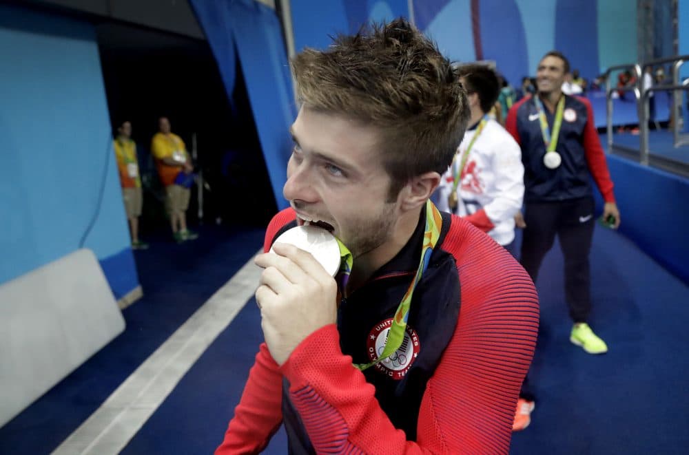 Silver medalist Michael Hixon bites his medal while looking at supporters after the men's synchronized 3-meter springboard diving final in the 2016 Olympics on Wednesday, Aug. 10, 2016 in Rio. (Wong Maye-E/AP)
