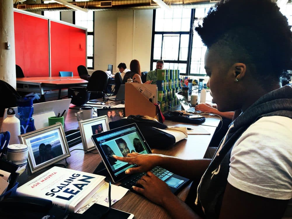 Rica Elysee demonstrates her BeautyLynk website in a workspace at MassChallenge. (Simón Rios/WBUR)