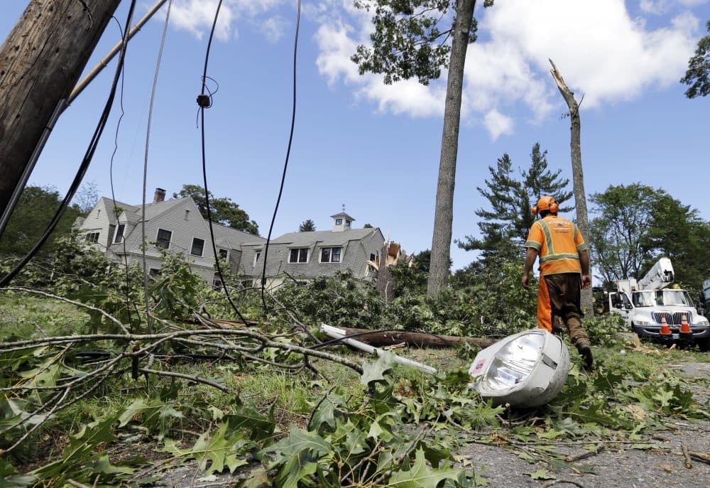 A tree removal worker walks past a downed light pole and lines. The EF-1 tornado knocked out power and caused damage to dozens of homes. (Elise Amendola/AP)