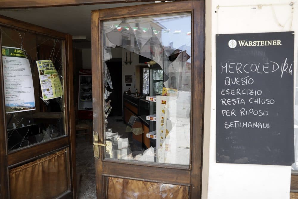 Damaged houses are reflected in the shattered window of a cafe in Accumoli, Italy. (Andrew Medichini/AP)