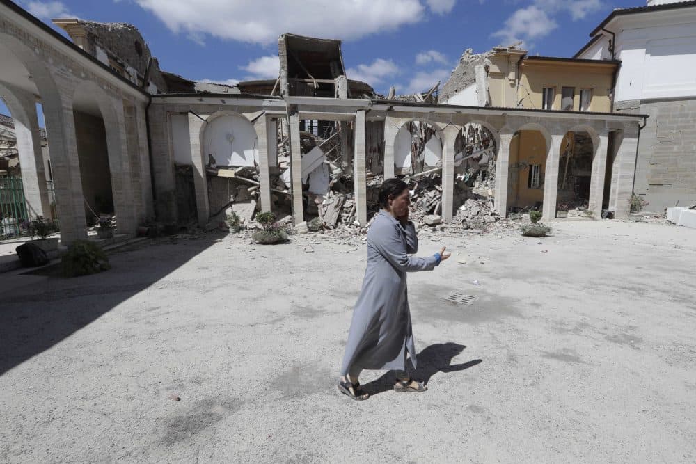 A nun talks on the phone as she walks in the courtyard of a damaged convent following the earthquake. (Alessandra Tarantino/AP)