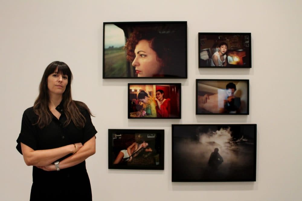 Eva Respini, the Barbara Lee Chief Curator at the ICA, stands in front of a wall of photographs by Nan Goldin. (Amy Gorel for WBUR)