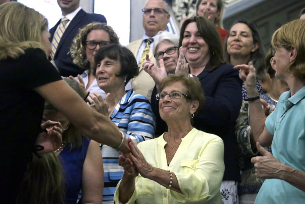 Dorothy Simonelli smiles as Lt. Gov. Karen Polito shakes her hand during the bill-signing ceremony Monday. Simonelli fought for equal pay as a cafeteria worker in the late 1980s in Everett. (Elise Amendola/AP)