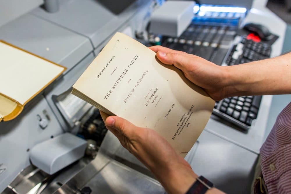 Harvard's Library Innovation Lab is working to digitize nearly 40 million pages of case law so the public can access it online and for free. Here, a case law book that has been freed from its binding is ready to go through a high-speed scanner. (Brooks Kraft/Harvard Law School)