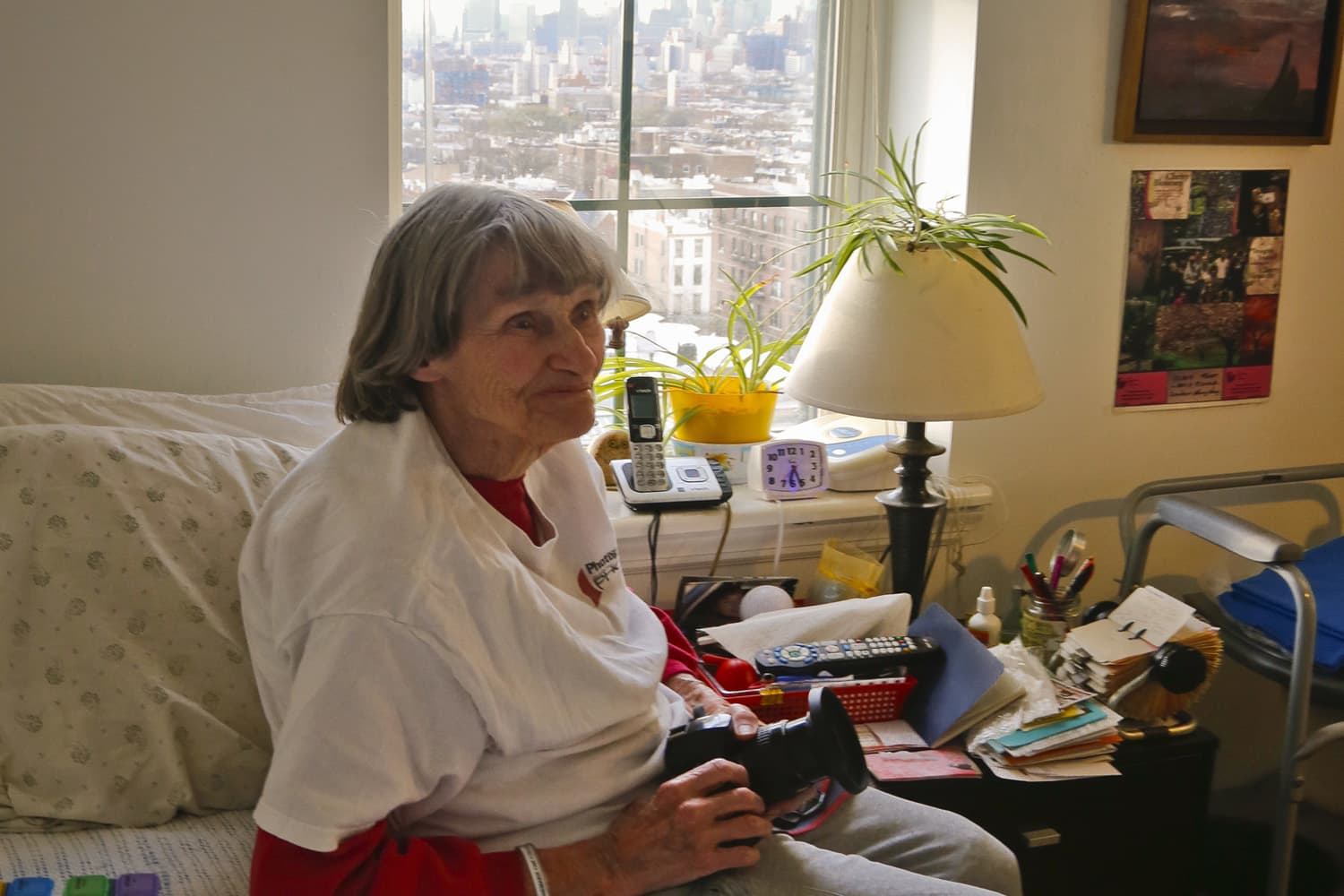 Annemarie Mogil sits in her bedroom holding the camera she uses to make photographs from her window at the Prospect Park Residence, an assisted living apartment complex for seniors, in Brooklyn, N.Y. (Bebeto Matthews/AP)