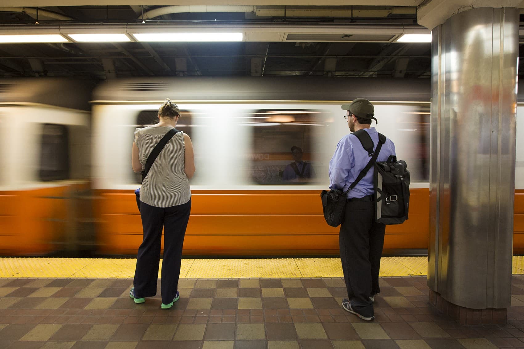 Commuters wait on the platform as an Orange Line train enters Downtown Crossing station. (Jesse Costa/WBUR)