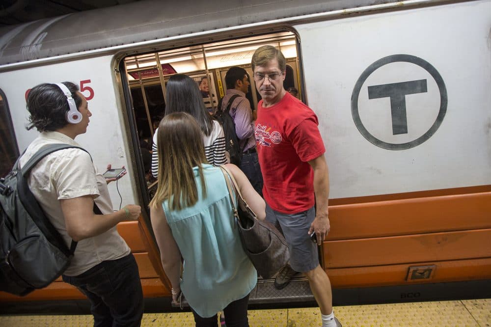 Greg Dietchenko navigates his way around a flurry of commuters boarding an MBTA Orange Line train. (Jesse Costa/WBUR)