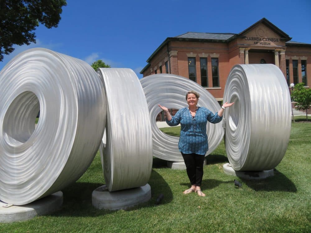 Clarinda Carnegie Art Museum Director Trish Okamoto with sculptor Brad Howe's 'Wall of Eyes' -- which one Clarinda farmer at first mistook for air-conditioning ducts. (C.J. Janovy/KCUR)
