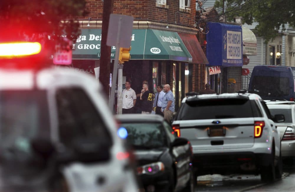 Police and officials gather in the doorway of a building early Monday, Sept. 19, 2016, in Elizabeth, N.J. A suspicious device found in a trash can near a train station exploded early Monday as a bomb squad was attempting to disarm it with a robot, officials said. (Mel Evans/AP)