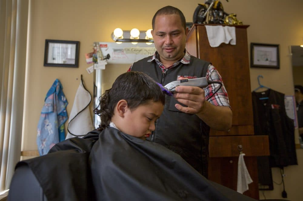 Luis Feliciano cuts the hair of a young boy at the newly opened Brother's Barber Shop on Main Street in Fitchburg. Feliciano worked with NewVue Communities, a local community development corporation, to open his business. (Jesse Costa/WBUR)