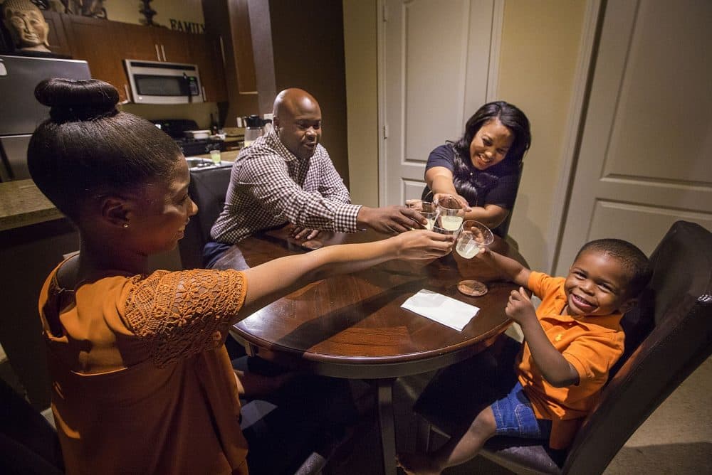 The Skinner-Seney family, (from left to right) J'Nye Sibley (14), Wedly Seney, J' Neen Skinner-Seney, and Loyalty Seney (2) toast around the table which they recently bought with the help of WBUR listeners. (Jesse Costa/WBUR)