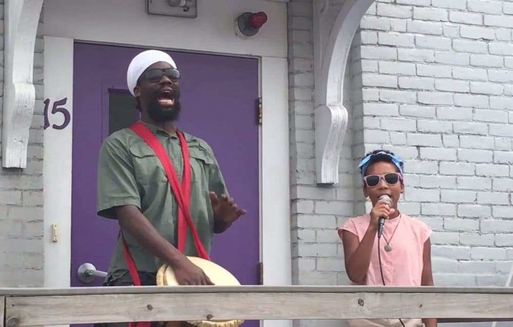 Inari Jade Higgins Barrett, right, sings &quot;Fly Like a Dove&quot; at the Louis D. Brown Peace Institute accompanied by her father, Toussaint Liberator. (Vimeo screenshot)