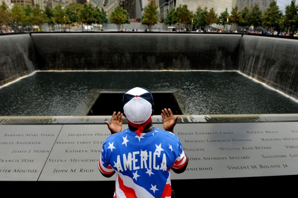 Albert Biatta, of Queens section of New York prays while standing front of the inscribed name of his uncle Antoine Biatta at the edge of the North Pool during memorial observances on the 13th anniversary of the Sept. 11 terror attacks on the World Trade Center in New York, Thursday, Sept. 11, 2014. Family and friends of those who died read the names of the nearly 3,000 people killed in New York, at the Pentagon and near Shanksville, Pennsylvania. (AP Photo/Justin Lane, Pool)