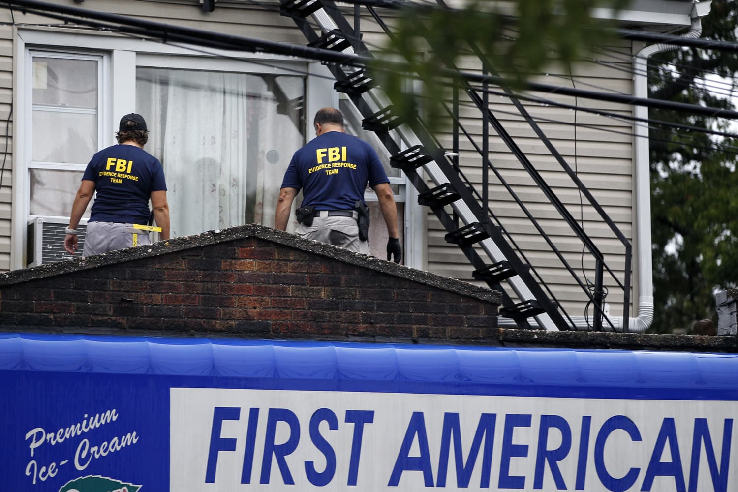 FBI agents walk around the roof outside an apartment during an investigation at a building in Elizabeth, N.J. FBI agents are searching the apartment in New Jersey that is tied to Ahmad Khan Rahami wanted for questioning in the New York City bombing. (Mel Evans/AP)