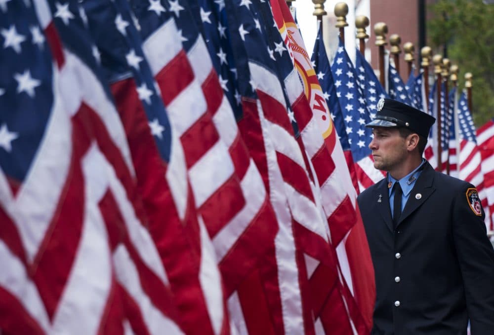 An FDNY firefighter walks among flags at the FDNY Memorial Wall on Sunday, Sept. 11, 2016, on the 15th anniversary of the attacks on the World Trade Center in New York. (Craig Ruttle/AP)