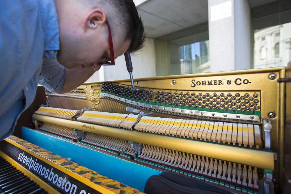 Wilson wears earplugs to block sound interference as he tunes a piano at the Christian Science Plaza. (Jesse Costa/WBUR)