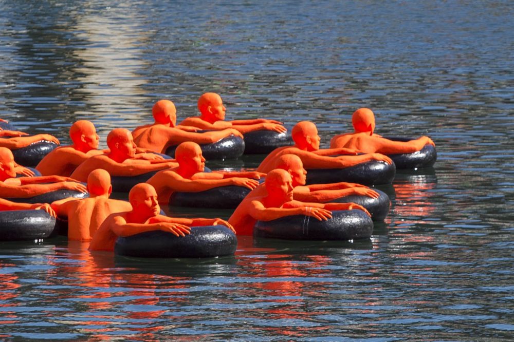 Ann Hirsch and Jeremy Angier's in “SOS (Safety Orange Swimmers)” floating in Boston's Fort Point Channel. (Jesse Costa/WBUR)