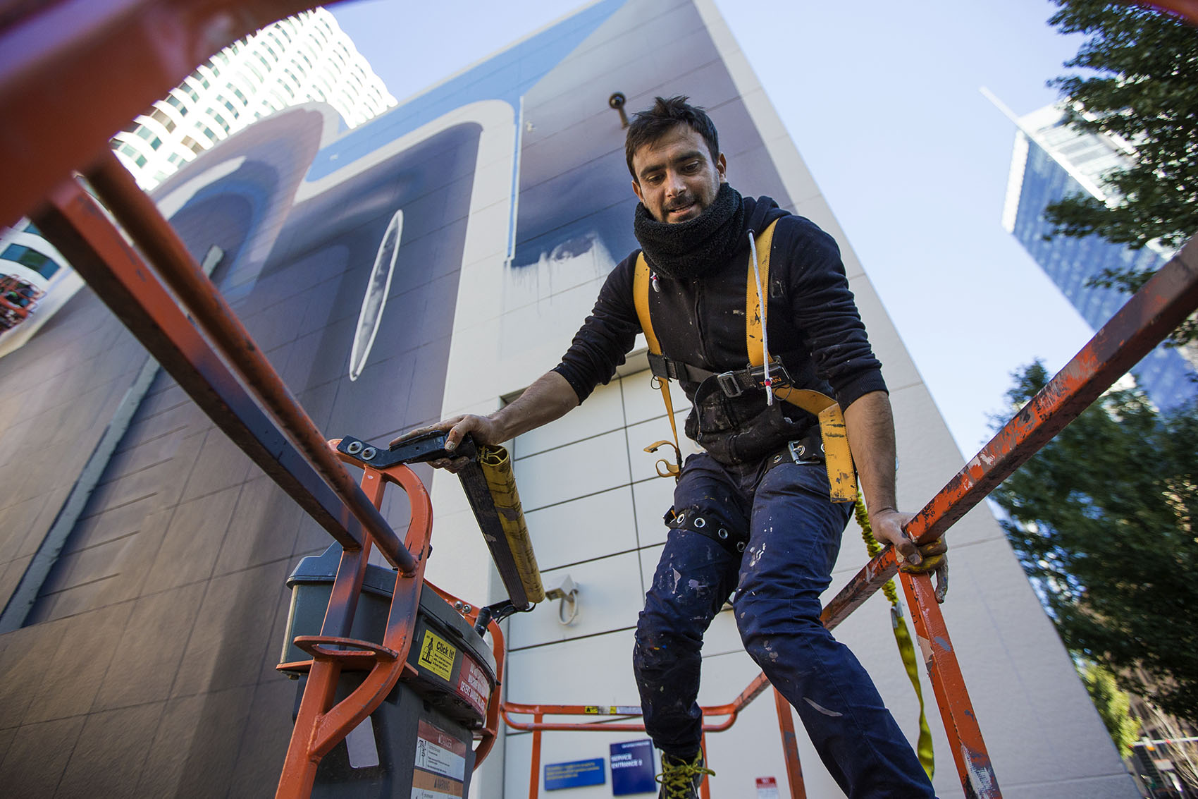 Iranian artist Mehdi Ghadyanloo climbs into a cherry picker as he works on the latest mural to go up on the Rose Kennedy Greenway in Dewey Square. (Jesse Costa/WBUR)