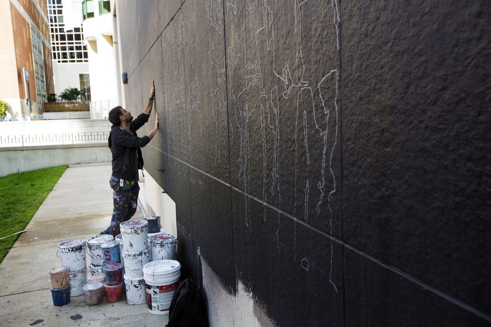 Ghadyanloo examines the texture of the wall before sketching out his design. (Jesse Costa/WBUR)