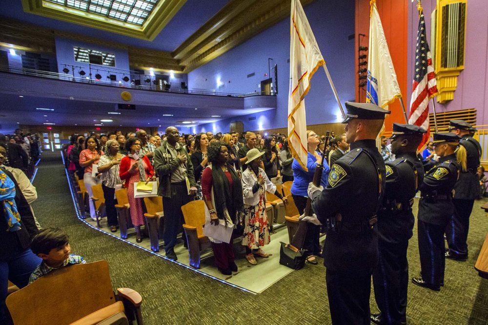 New U.S. citizens take the Oath of Allegiance inside the auditorium at Malden High School. (Jesse Costa/WBUR)