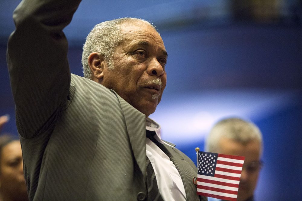 Jose Gomes, of Cape Verde, raises his hand to take the Oath of Allegiance to become an American citizen. (Jesse Costa/WBUR)